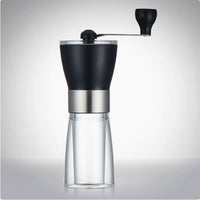 Black manual coffee grinder with clear glass base and stainless steel band, modern kitchen accessory